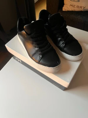 Svarta sneakers från Selected Homme - Svartas sneakers från Selected Homme i stilren design med vita. Dem e använda men fortfarande i bra skick. 