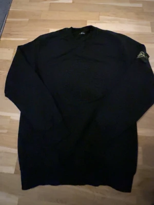 Stone Island Tröja - En fin tröja från stone island i färgen svart. Tröjan har en stone island logga på mitten av tröjan och en på armen. Tröjan är storlek L men passar M jättebra.