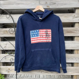 Ralph Lauren USA Hoodie - Asfet Hoodie från Ralph Lauren. Eftertraktat motiv. Fint skick. Storlek L (14-16), passar som en vanlig XS skulle jag säga. Hör gärna av er vid funderingar🙌🏻🙌🏻