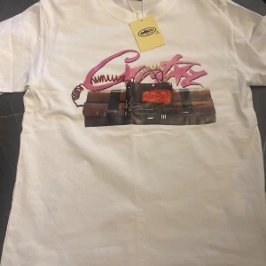 Vit t-shirt NOTIME4LUV med tryck - Säljer en vit t-shirt från NOTIME4LUV med coolt tryck framtill i rosa och svart, föreställande graffiti och en digital timer. Baksidan har stor svart text 'NOTIME4LUV'. Klassisk passform och rund hals. Perfekt statement-plagg för dig som gillar streetwear.