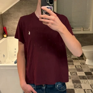 Polo Ralph Lauren t-shirt – Vinröd - Klassisk t-shirt från Polo Ralph Lauren i vinröd/bordeaux med vit broderad logga. Stilren bas-tee som funkar året runt och är lätt att matcha till jeans eller shorts. Bekväm och i fint skick.  ✔️ Storlek: S ✔️ Färg: Vinröd/Bordeaux ✔️ Skick: Mycket bra – inga fläckar eller hål.           Pris kan diskuteras!
