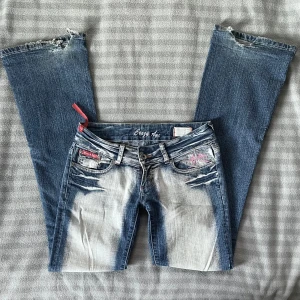 Crazy age lågmidjade utsvängda jeans   - Jätte lågmidjade jeans från crazy age i strl S, färgen i verkligheten är som de 2 första bilderna // midja 37cm tvärsöver (+ stretch), innerbenslängd 82cm, grenhöjd 16,5 // lite slitna hälar som man ser på bilden ❤️ 