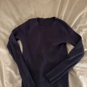Mörkblå ribbad croppad tröja - Säljer en mörkblå, ribbad och croppad tröja med lång ärm och rund halsringning. Tröjan är figurnära. Från Dazy i storlek L