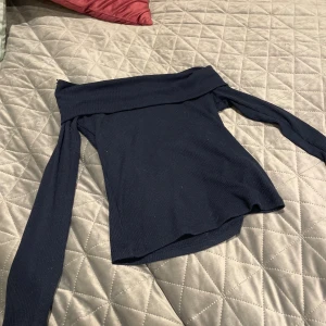Marinblå offshoulder topp Gina Tricot - Säljer en marinblå ribbad offshoulder topp från Gina Tricot i storlek XS. Toppen har långa ärmar och är figurnära med snygg croppad passform. Perfekt för dig som gillar stilrena och trendiga plagg med lite edge.