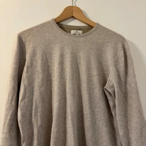 Beige stickad tröja Hansen & Jacob - Snygg beige stickad tröja från Hansen & Jacob i storlek M. Tröjan har rund halsringning och är långärmad, perfekt för dig som gillar stilrena och neutrala plagg. Materialet är mjukt och skönt, passar dig som vill ha en enkel men klassisk look.