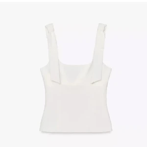 Vit linnetopp med knytband - Supersnygg vit linnetopp med breda axelband som knyts i rosetter. Toppen har en rak, croppad passform och är perfekt till jeans eller kjol. Stilren och enkel design som känns fräsch och modern.