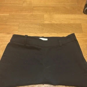 Svart kortkjol med rå kant - Svart kortkjol med bälteshällor och rå, fransig nederkant. Kjolen har två bakfickor och en enkel, stilren design. Perfekt för dig som gillar en clean och minimalistisk look.