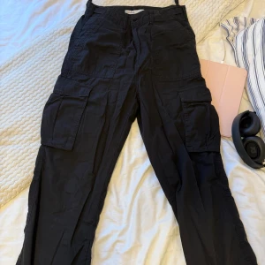 Svarta cargo byxor från Bershka - Svarta cargo byxor från Bershka med raka ben och flera stora fickor på sidorna och bak. Har även en justerbar midja.