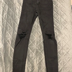 Svarta skinny jeans från 157, XS - Svarta jeans från 157 i modellen Snake, storlek XS. De har tight passform och skinny stil med slitna detaljer vid knäna för en edgy look. Klassisk femficksdesign och tillverkade i stretchigt bomullsmaterial för skön komfort.