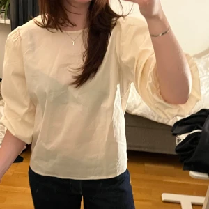 Beige blus  - Supersöt beige blus med puffiga trekvartsärmar och svart rosett i ryggen. 