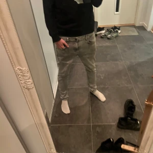 Grå jeansbyxor i storlek 32/30 - Säljer ett par grå jeansbyxor i storlek 32/30 med klassisk femficksdesign. Byxorna har en rak passform och är tillverkade i mjukt jeanstyg. Snyggt slitna detaljer och neutral grå färg som passar till det mesta. Perfekt för dig som gillar en enkel och clean look.