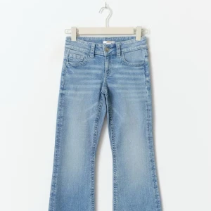 Bootcut ljusblå jeans med broderad ficka - Snygga ljusblå bootcut jeans med broderad bakficka och små paljetter. Jeansen har klassisk femficksdesign, knapp och dragkedja framtill samt mjukt tvättad denim. Perfekt för dig som gillar detaljer och en avslappnad stil,storleken är 158 men passar som en s.