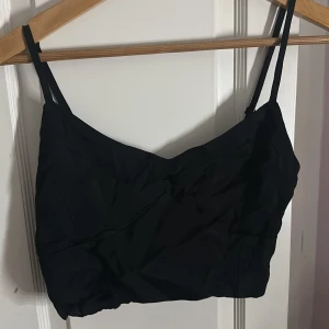 Svart korsett-topp med dragkedja - Snygg svart korsett-topp från Chiquelle med justerbara smala axelband och dragkedja i sidan. Toppen har en croppad passform och är tillverkad i mjukt viskosmaterial som ger en skön känsla. Perfekt att styla med höga jeans eller kjol. Använd endast i butik ‼️kommer inte till användning.