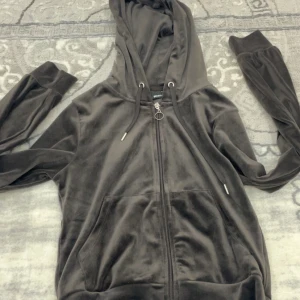 Mörkbrun kofta - Säljer en mörkbrun hoodie från Gina Tricot i mjuk velour med huva och snörning. Tröjan har långa ärmar, fickor framtill och en snygg dragkedja med ringdetalj. Perfekt för chill dagar och sköna outfits. Har aldrig tagit på mig den och köpte detta året