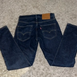 Levi's 512 mörkblå jeans W28 L30 - Säljer ett par mörkblå Levi's 512 jeans med klassisk femficksdesign och snygga kontrastsömmar. Jeansen har normal passform med smalare ben och är tillverkade i slitstarkt denim. Perfekta för dig som gillar en stilren och tidlös look.