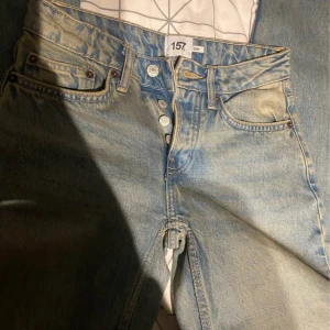 Ljusblå jeans från 157 i XXS - Säljer ett par ljusblå jeans från 157 i storlek XXS. Klassisk femficksmodell med knäppning fram och snyggt slitna detaljer. Perfekta för dig som gillar en avslappnad och trendig look.