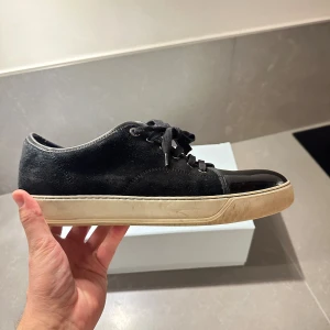 Lanvin svarta storlek 9 (43) - Snygga svarta sneakers från Lanvin i mocka och blank cap toe. Skorna har snörning med metallöglor och en vit platt sula. Box medföljer.