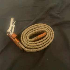 Beige flätat bälte från Jack & Jones - Säljer ett snyggt beige flätat bälte från Jack & Jones med detaljer i brunt skinn och ett stilrent silverfärgat spänne. Perfekt för dig som vill ha en clean och modern look. Bältet har en klassisk design med tydlig branding på skinnet.