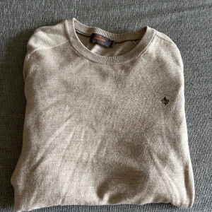 Beige tröja från Morris - Snygg beige tröja från Morris med rund halsringning och diskret broderad logga på bröstet. Tröjan är i mjuk merinoull och har ärmar med ribbade muddar. Perfekt för lager-på-lager och enkel att matcha med jeans eller chinos.  Nypris 1400kr. Hör av er vid intresse/ frågor!