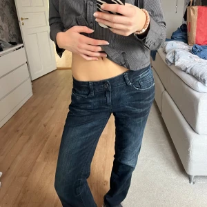 Mörkblå Replay jeans med broderade fickor - Säljer ett par mörkblå jeans från Replay med snygga broderade detaljer på bakfickorna. Jeansen har låg midja och klassisk femficksdesign. Materialet är jeans och passformen är rak med en något loose känsla. Perfekta för dig som gillar en avslappnad men stilren look.