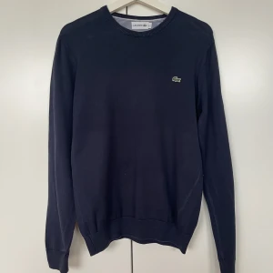 Mörkblå stickad tröja från Lacoste - Mörkblå stickad tröja från Lacoste, knappt använd och i bra skick! Nypris: 1.000kr. Strl, S