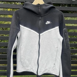 Nike tech  - Jag säljer en Nike tech generation 2 i svart vit och grå.  Tröjan är i bra skick endast lite nopprig på fåtal ställen.  Tröjan är sparsamt använd och väl omhändertagen. 