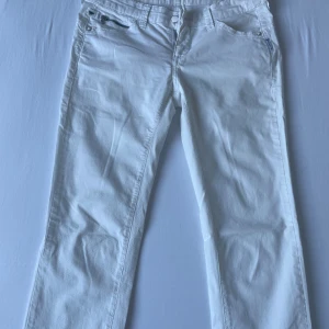 Vita low waist jeansbyxor från Armani Jeans - Snygga vita jeansbyxor från Armani Jeans med klassisk femficksdesign och silverfärgad dragkedja. Bakfickorna har broderad logga och metallmärke. Byxorna syddes från straight till bootcut. Finns grön ”fläck” märket lämna efter sig, syns på näst sista bild. Inga konstigheterannars💕
