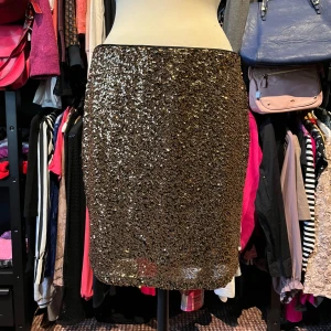 Glittrig guld kjol från H&M - Snygg glittrig guld kjol från H&M i kort modell. Kjolen är täckt av paljetter som ger en riktigt festlig look och har en rak passform. Tillverkad i 100% polyester. Perfekt för dig som vill sticka ut med stil.