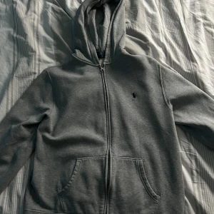 Grå zip up hoodie - Säljer en grå zip up hoodie från ralph lauren som tyvärr är för liten för mig. Den är xl i barn storlek så den passar dig om du är runt 160-170 cm lång! 