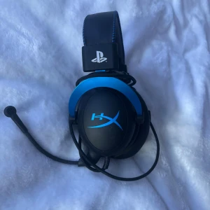 HyperX Cloud Stinger Core PS4 - HyperX Cloud Stinger Core gamingheadset för PlayStation, med blå detaljer och PlayStation-logga. Kabelanslutet med justerbar mikrofon och bekväma over-ear-kuddar. Bra skick, inga synliga defekter eller slitage. Perfekt för spel och kommunikation. 