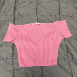 Rosa ribbad offshoulder topp från Zara - Säljer en rosa ribbad offshoulder topp från Zara. Toppen har croppad passform, korta ärmar och en snygg v-ringning framtill. Passar jätte bra för dig som vill ha en tajt magtröja 