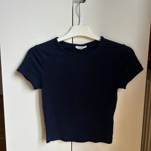 Mörkblå croppad topp Basically Basics - En basic marinblå tight t-shirt ifrån Gina tricot, extremt bekväm att ha på sig! Inte använd mycket, defenetivt mindre än 10 gånger. Storlek xs, skriv gärna ifall du hade velat se fler bilder!🥰