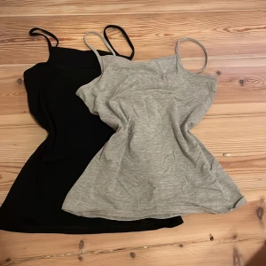 2 linnen från H&M, svart & grå - Två enkla och stilrena linnen från H&M i storlek 158/164, XS-S. Ett linne är svart och det andra är ljusgrått, båda med smala axelband och rak passform. Perfekta att bära som de är eller under en skjorta. Materialet är mjukt och stretchigt, troligtvis bomullsmix. Hör av er vid intresse!!🥰🥰