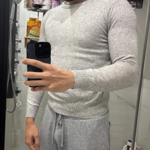 Ljusgrå stickad tröja med rund hals - Snygg ljusgrå stickad tröja med rund hals och ribbade muddar vid ärmslut och nederkant. Tröjan har en slim passform och är långärmad, perfekt för dig som gillar stilrena och enkla plagg. Passar till både jeans och mjukisbyxor. Älskar den. Men den e då för liten för mig däröför säljs den. Jätte skön nu på vinter. 100% MERIONULL