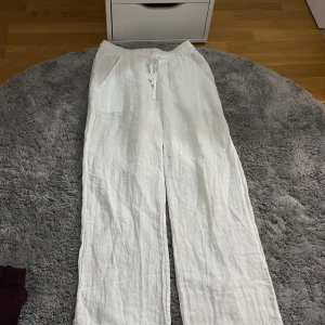 Vita linnebyxor från Cheese, stl S - Säljer ett par vita linnebyxor från Cheese i storlek S. Byxorna har resår i midjan med snörning och raka, lösa ben. Perfekta för varma dagar och chill vibes. Luftigt material och klassisk look.