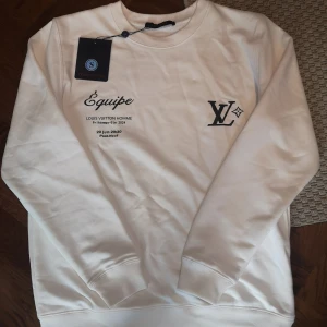 Louis Vuitton sweater - Exklusiv vit crewneck från Louis Vuitton med svart LV-logga och tryck både fram och bak. Säljer då den är för stor för mig helt nytt skick fick den som en överraskning när ja var i London av mina föräldrar 