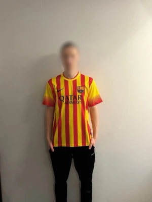 Barcelona Messi 13/14 borta - Säljer en Barcelona tröja med Messi och nummer 10 på ryggen. Säsongen 13/14 så spelade Barcelona i detta borta ställ med snygga gula och röda linjer som går vertikalt över hela tröjan. Perfekt för dig som älskar Barcelona och vill bära ett snyggt borta ställ🐐. 