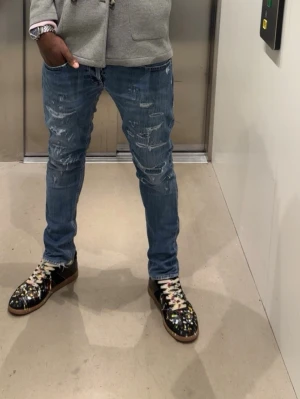 Blå skinny jeans från dondup - Säljer ett par blå skinny fit jeans från  dondup med slitna detaljer och klassisk femficksdesign. Jeansen har en smal passform och är tillverkade i ett mjukt denimtyg som sitter tajt längs benen. Perfekta för dig som gillar en modern och avslappnad look.