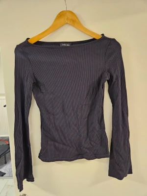 Svart ribbad långärmad topp - Snygg svart ribbad topp från White Rose med lång ärm och figurnära passform. Toppen har en enkel, stilren design med rund halsringning och tunna ribbade ränder som ger en modern känsla.