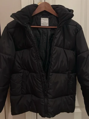Nästan ny svart pufferjacka från Index - Svart supervarm och mysig pufferjacka från Index som är perfekt vid skidåkning 🎿 Perfekt för kyliga dagar och enkel att matcha med olika outfits. Storleken står ( 12-13 år men skulle säga nästan vuxen M) Nypris 699kr. Tillverkad i syntetmaterial och varm fleece 🌟