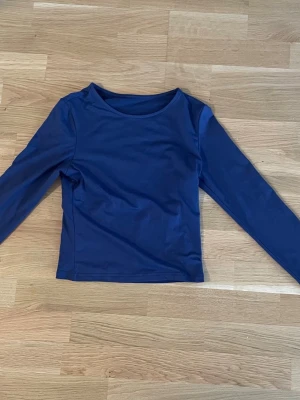 Mörkblå långärmad topp - En enkel och stilren mörkblå långärmad topp med rund halsringning. Toppen har en tight passform och är tillverkad i ett mjukt, stretchigt material som känns bekvämt mot huden. Perfekt att matcha med jeans eller kjol för en clean look.