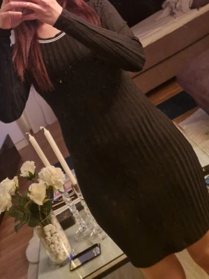 Svart ribbad långärmad klänning - Säljer en svart ribbad klänning med lång ärm och rund halsringning. Klänningen har en kroppsnära passform och är tillverkad i ett stretchigt material som framhäver figuren. Perfekt för dig som gillar en stilren och enkel look.