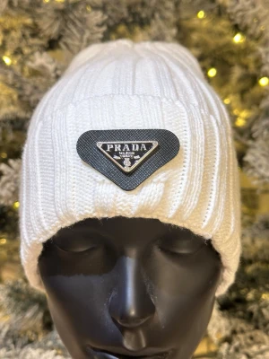 Vit ribbstickad mössa - Snygg vit ribbstickad mössa med klassisk passform. Perfekt för kalla dagar och enkel att matcha med olika outfits. Tidlös design som funkar året runt.