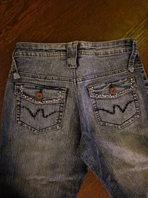 Vintage jeans - Fick ärva dessa tillsammans med massa andra jeans från en äldre släkting, de är midwaist, har knappar i bak och är bootcut. Det saknas en knapp i fram, men byxorna funkar ändå.  Har en till annons på  min sida med exakt likadana jeans fast utan saknad av knapp!