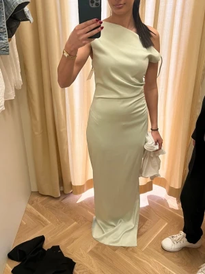 Ljusgrön långklänning i satin  - Använd en gång. Bandet har varit uppsydd, så det finns ett litet märke kvar från sprättningen, men inget som syns eller påverkar klänningen när den är på. Jag är 155cm!