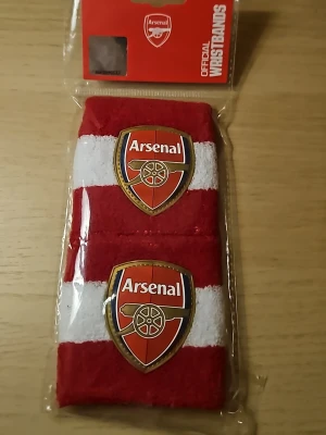 Arsenal svettband röd/vit - Två officiella Arsenal svettband i rött och vitt med klubbens logga broderad framtill. Perfekta för träning eller match, tillverkade i mjukt och stretchigt material som absorberar svett effektivt. Snygg accessoar för alla Arsenal-fans.