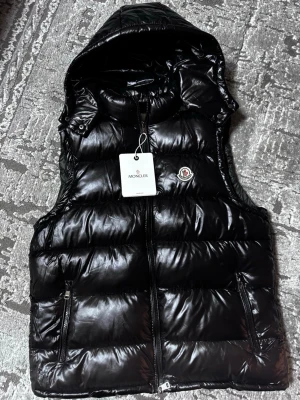 Svart dunväst från Moncler med luva - Helt ny, inte använd. Säljer den på grund av den e stor på mig. Pris diskuteras så kom med bud.