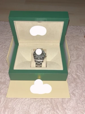 Stilren silverfärgad klocka i stål - Säljer en exklusiv silverfärgad klocka från …… med klassisk länkarmband i rostfritt stål. Klockan har en svart urtavla och vridbar ring med tydliga markeringar. Levereras i original grön box med beige inredning.