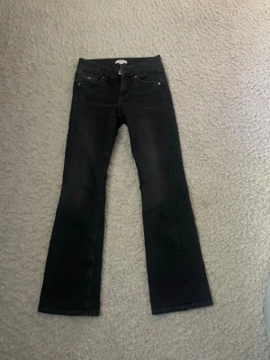 Svarta bootcut jeans - Snygga svarta bootcut jeans med klassisk femficksdesign och låg midja. Jeansen har en lätt utsvängd passform nertill och är tillverkade i ett mjukt denimtyg. Perfekta för dig som gillar en tidlös och avslappnad stil.