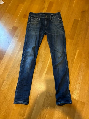 Replay Jeans - Säljer ett par Replay jeans i mörkblå. Klassisk femficksmodell med normal passform och raka ben. Jeansen är tillverkade i bomull med en snygg slitning på framsidan och bakfickor med diskreta sömmar. Perfekta för en avslappnad stil.
